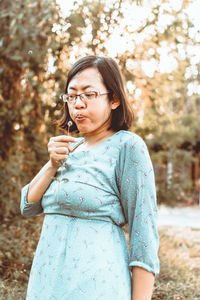 Mid adult woman standing against tree
