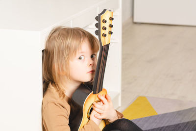Child at home learning to play the guitar. leisure and education at home