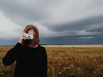 Man photographing on field against sky