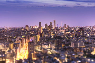 Aerial view of illuminated buildings in tokyo against blue hour purple sky.