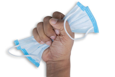 Close-up of hand holding plastic against white background