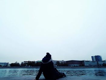 Rear view of woman standing in city against clear sky