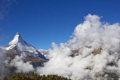 Low angle view of snow mountains against blue sky