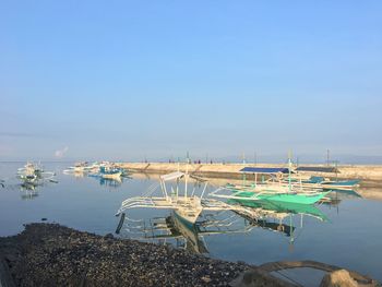 Sailboats moored in sea against sky