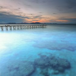 Pier over sea against sky during sunset