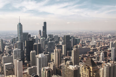 Aerial view of buildings in city against cloudy sky