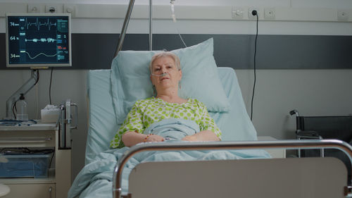 Portrait of senior woman resting on hospital bed