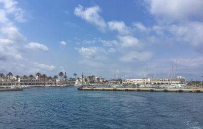 Scenic view of sea by buildings against sky