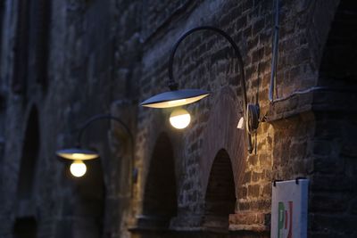 Illuminated electric lights mounted on brick wall of old building