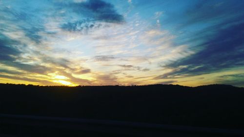 Silhouette landscape against dramatic sky during sunset