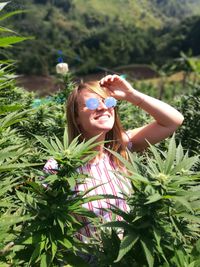 Portrait of smiling young woman standing against tree
