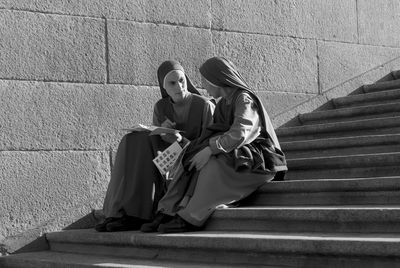 Couple sitting on staircase against wall