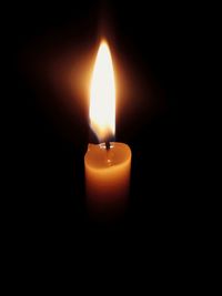 Close-up of burning candle against black background