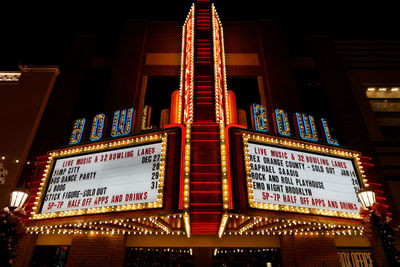 Low angle view of illuminated sign against building at night