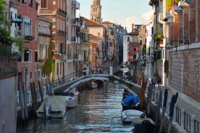 Boats moored on canal amidst buildings in city