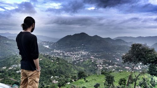 Rear view of man looking at mountains against sky