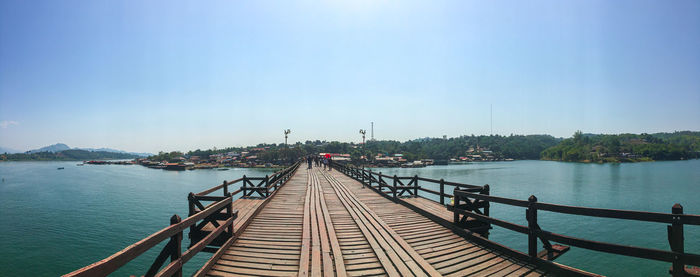 Pier over sea against clear blue sky
