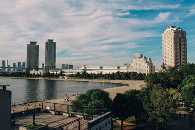 Buildings by river against sky in city