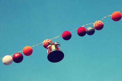 Low angle view of christmas decoration hanging against clear blue sky