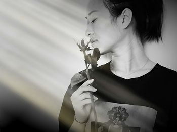 Young woman holding leaves against wall