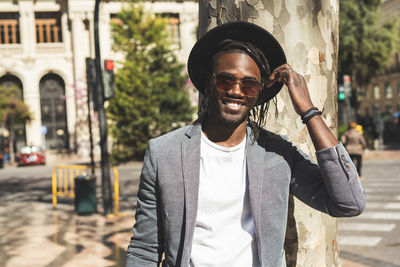 Portrait of smiling young man in hat at city