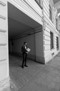 Full length of young man standing against building