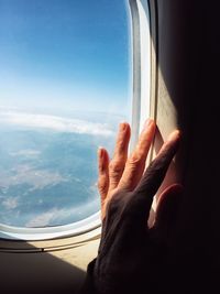 Cropped hand of woman touching airplane window