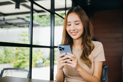 Portrait of young woman using mobile phone in cafe