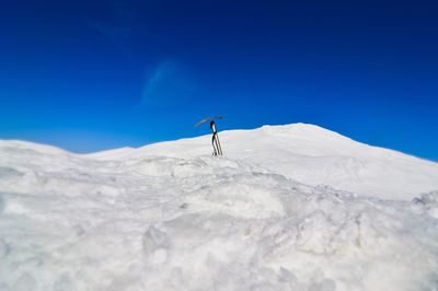 Person on snowcapped mountain against clear blue sky