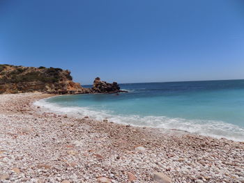 Scenic view of beach against clear blue sky