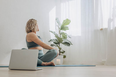 Rear view of woman using laptop at home