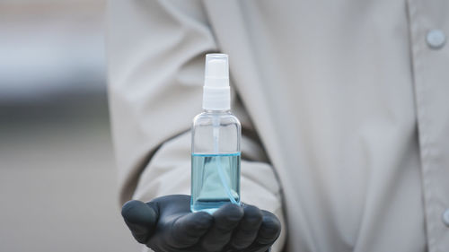Midsection of man holding spray bottle