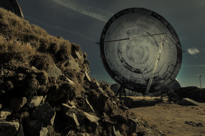 Low angle view of abandoned wheel on beach against sky