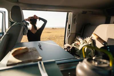 Rear view of woman with hand in hair seen though motor home