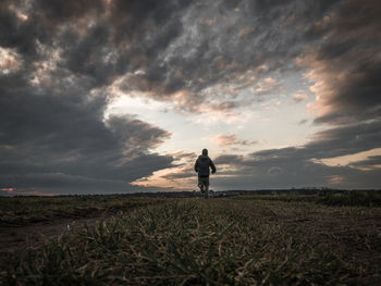 Man standing on field against sky during sunset