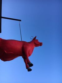 Low angle view of large red against clear blue sky