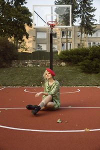 Full length of woman sitting at basketball court