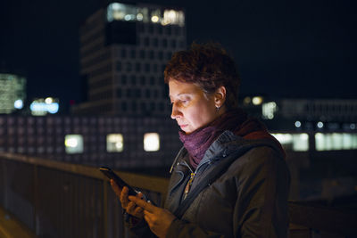 Portrait of man standing in illuminated city at night