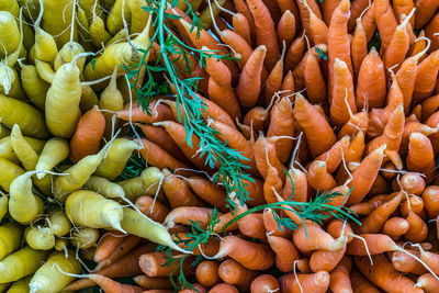 Full frame shot of yellow and orange carrots for sale at farmers market stall
