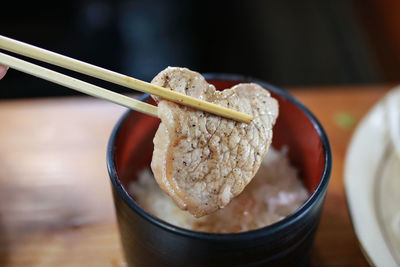 Close-up of chopsticks holding meat