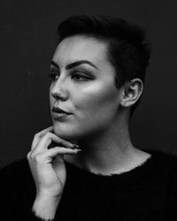 Portrait of young woman looking away against wall