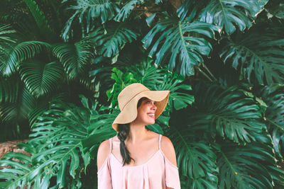 Portrait of young woman standing by tree