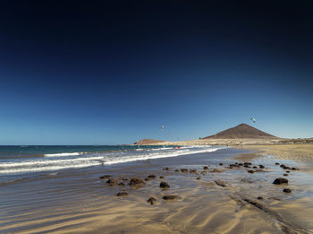 Scenic view of beach against clear blue sky