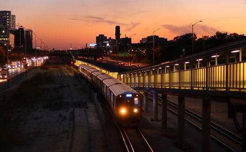 Illuminated bridge over river at sunset