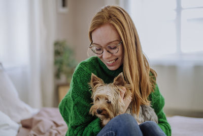 Happy woman sitting with yorkshire terrier at home