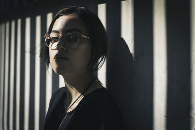 Portrait of young woman standing against wall