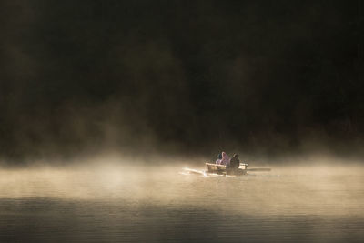 People in boat on lake during foggy weather