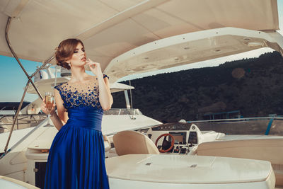 Beautiful young perfect girl in a dress and makeup, summer trip on a yacht with white sails 