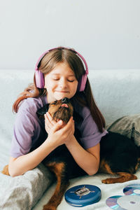 Girl with headphones playing with dog at home