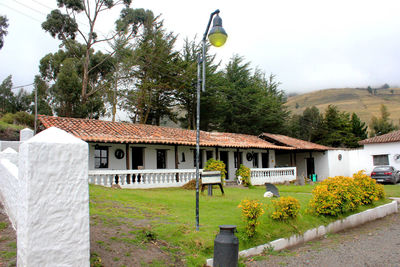 Built structure by trees and building against sky